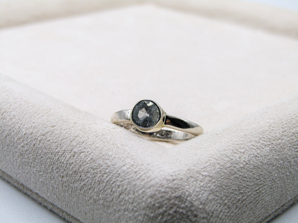 Silver ring with a black gemstone on a soft white surface