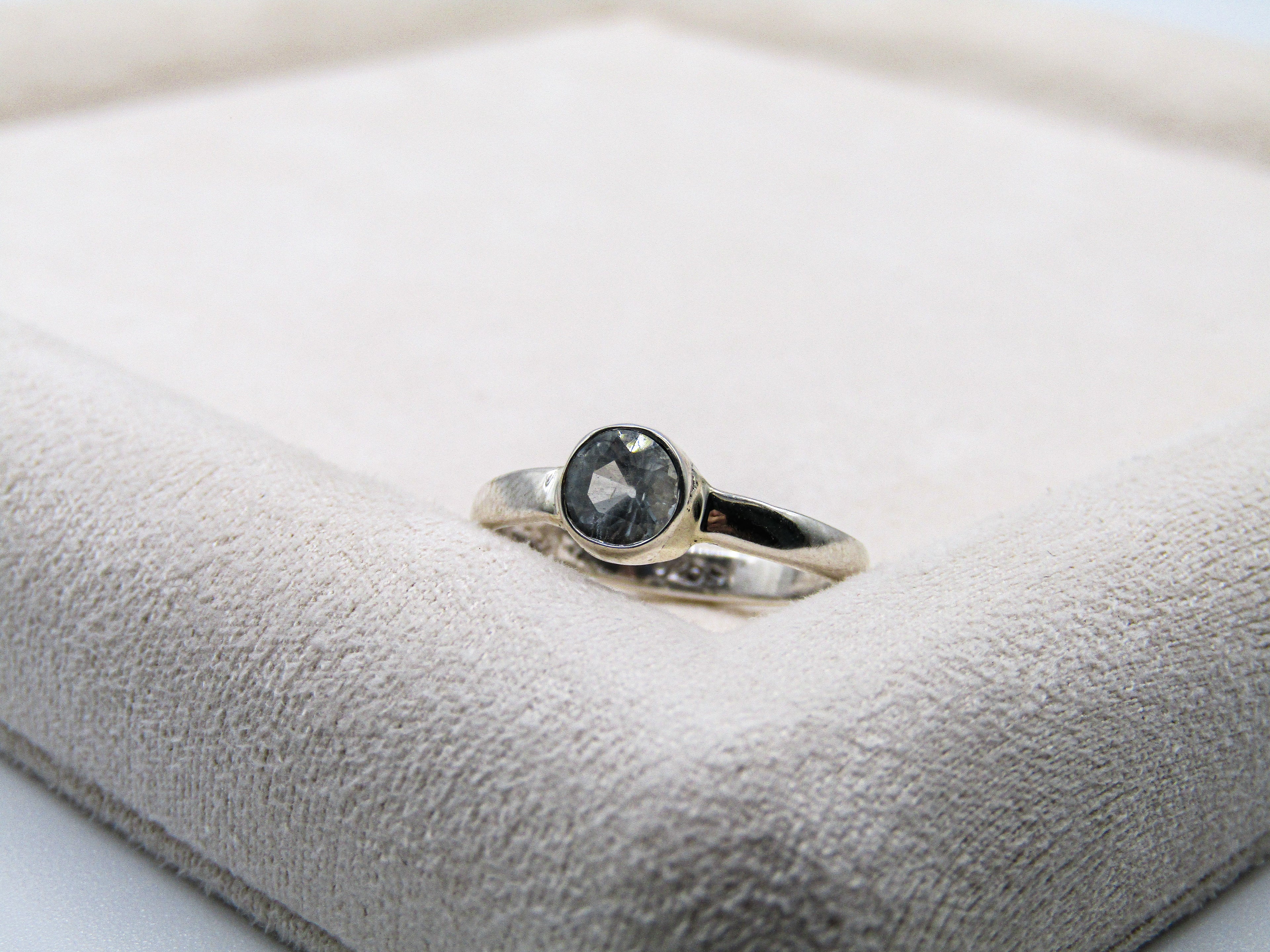 Silver ring with a black gemstone on a soft white surface