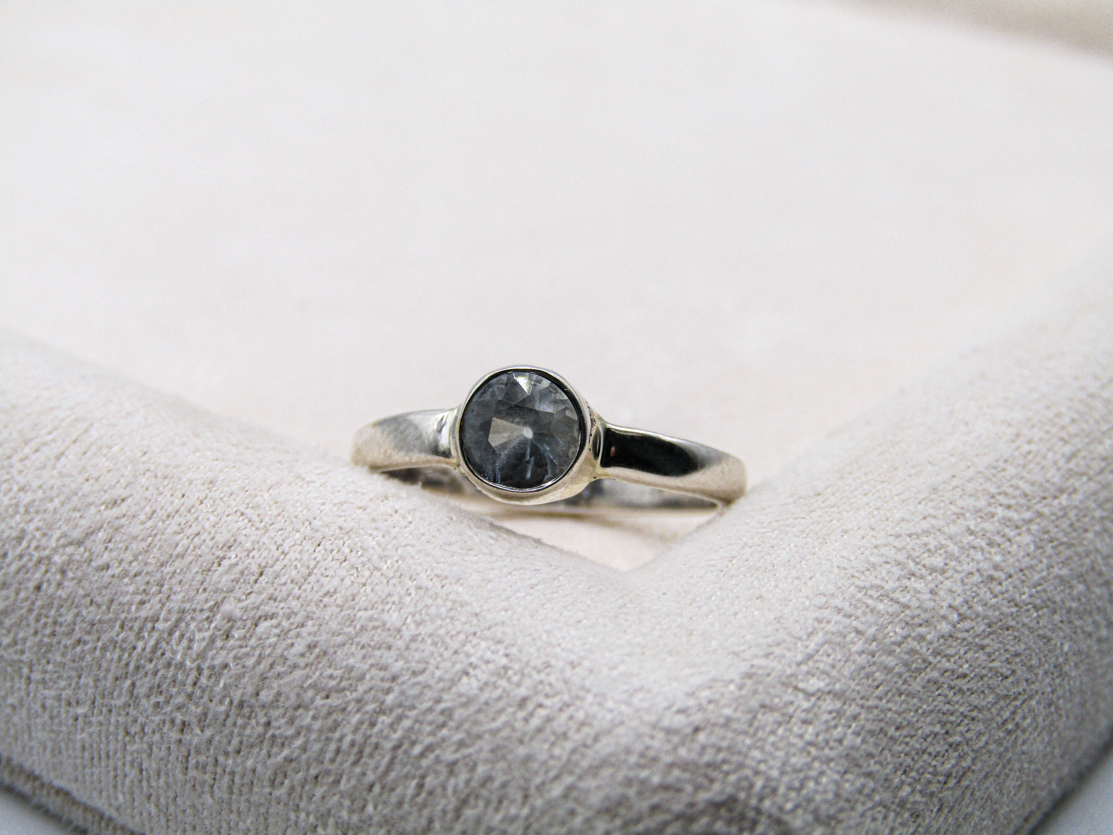 Silver ring with a black gemstone on a white cushion