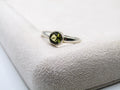 Silver ring with a green gemstone on a textured white surface