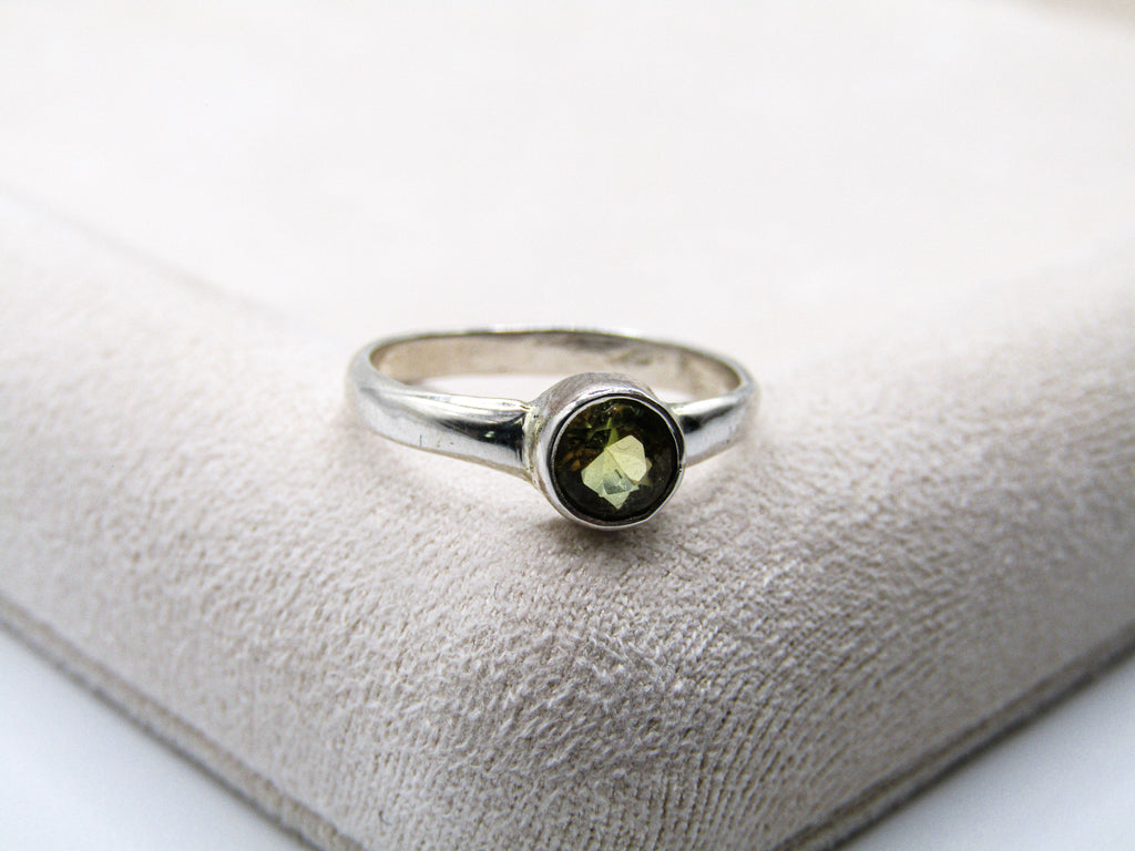 Silver ring with a green gemstone on a textured white surface