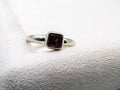 Silver ring with a red gemstone on a textured white surface