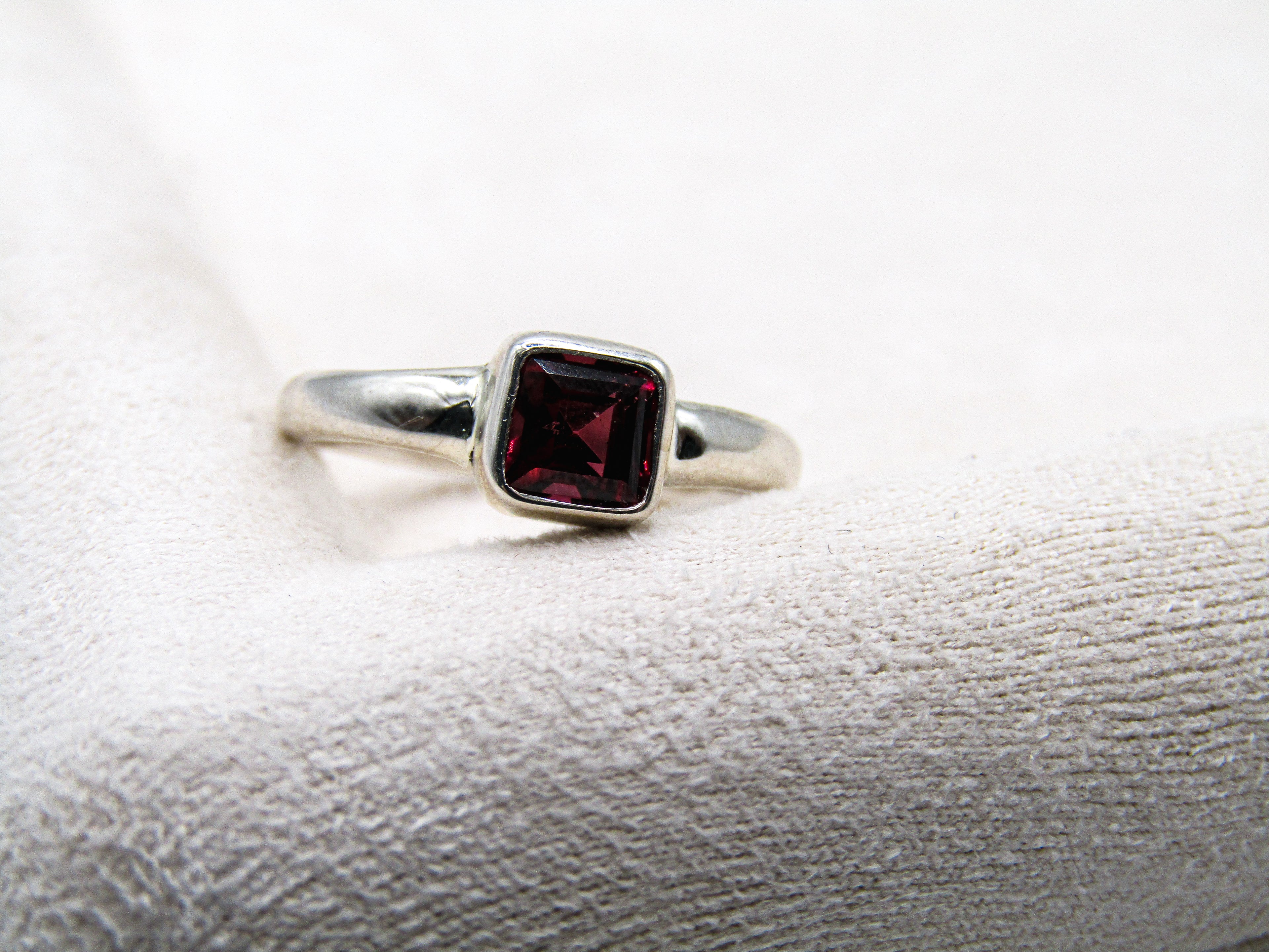 Silver ring with a red gemstone on a textured white surface