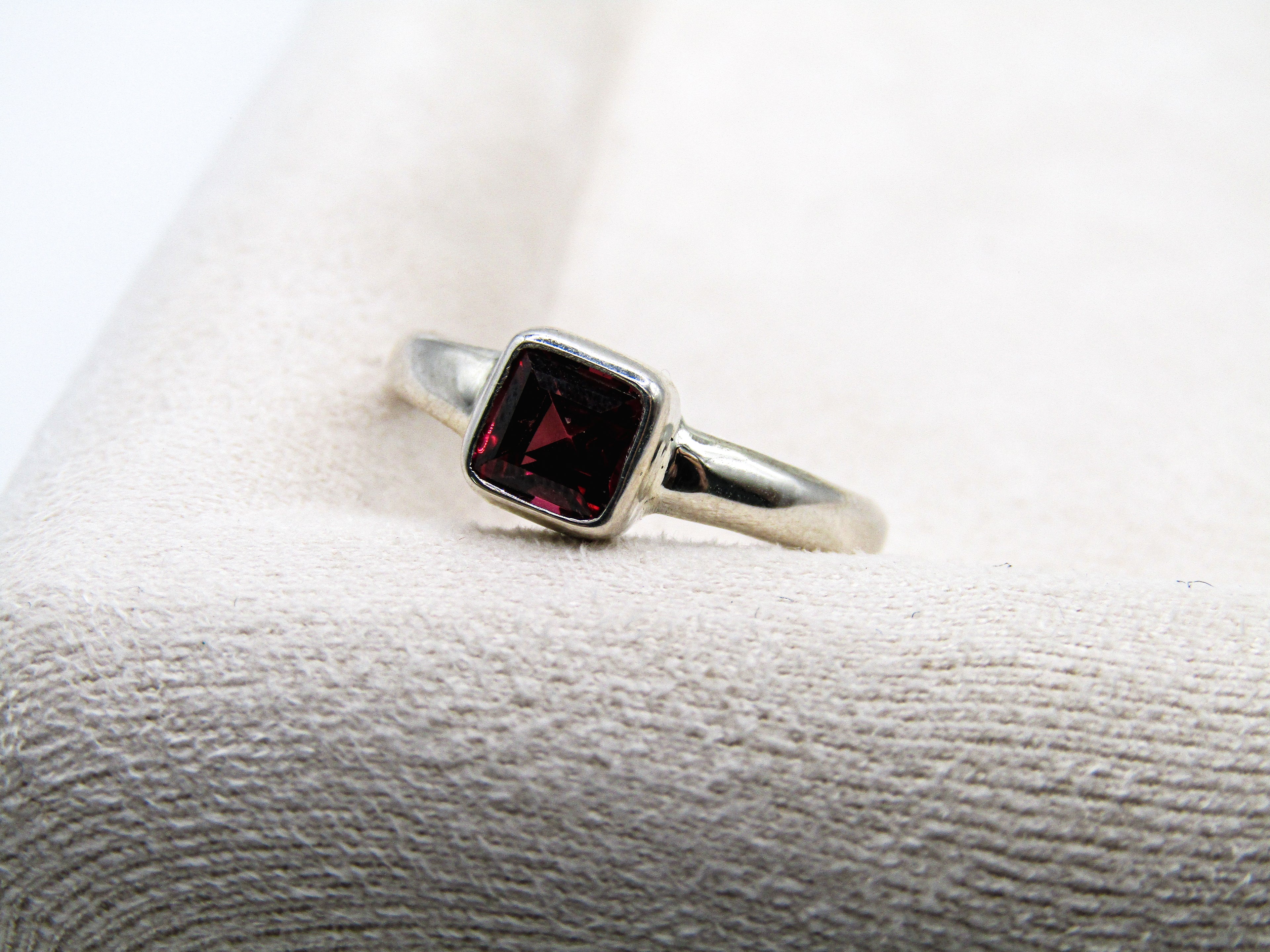 Silver ring with a red gemstone on a textured white surface