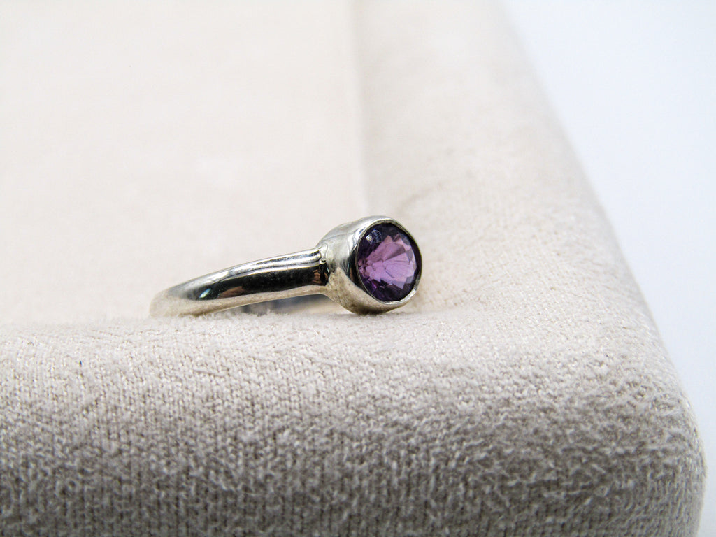 Silver ring with a purple gemstone on a textured surface