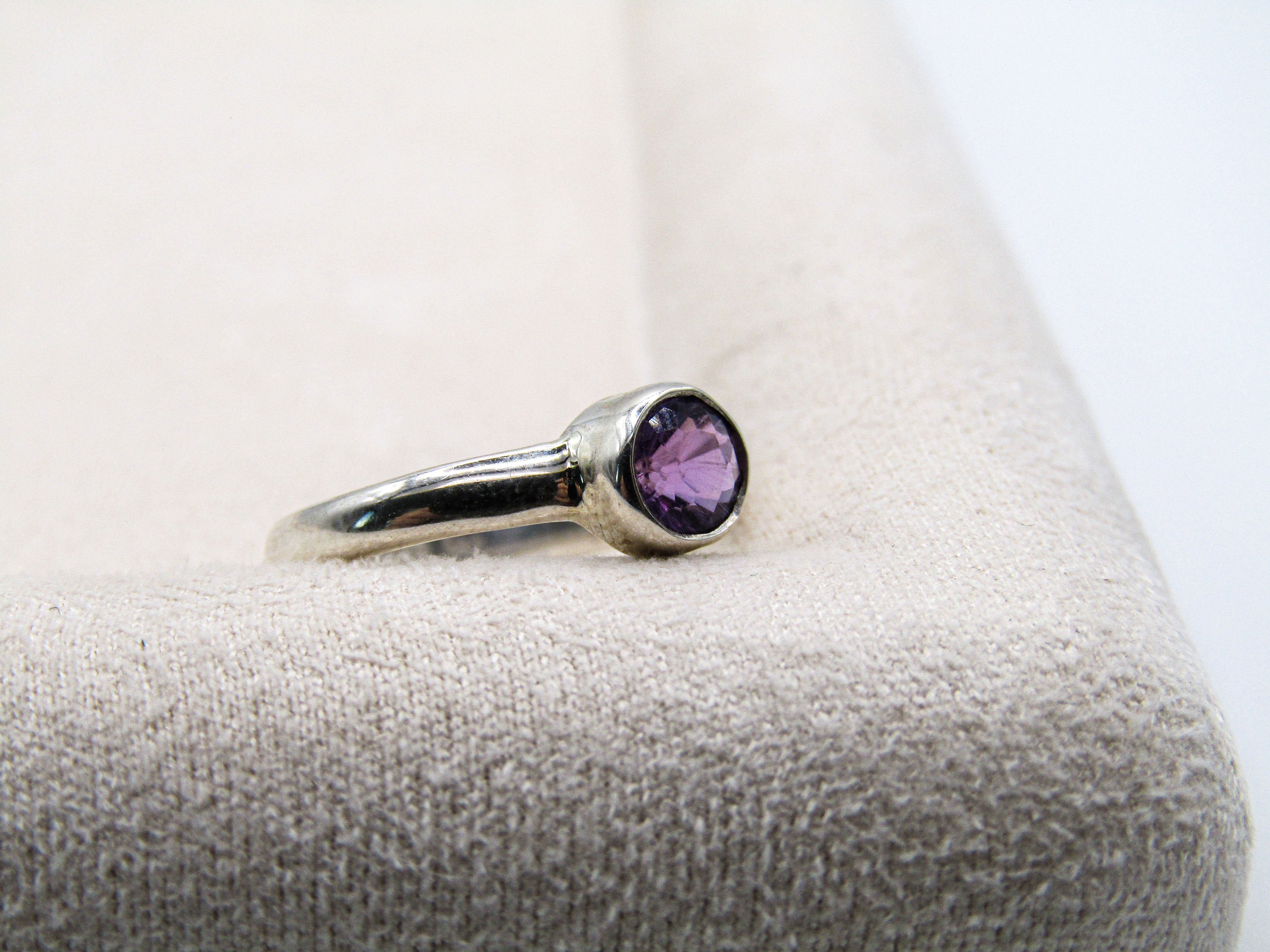 Silver ring with a purple gemstone on a textured surface