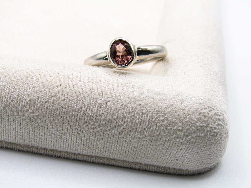 Silver ring with a brown gemstone on a textured gray surface