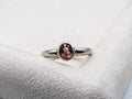 Silver ring with a pink gemstone on a textured white surface