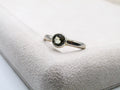 Silver ring with a green gemstone on a textured white surface