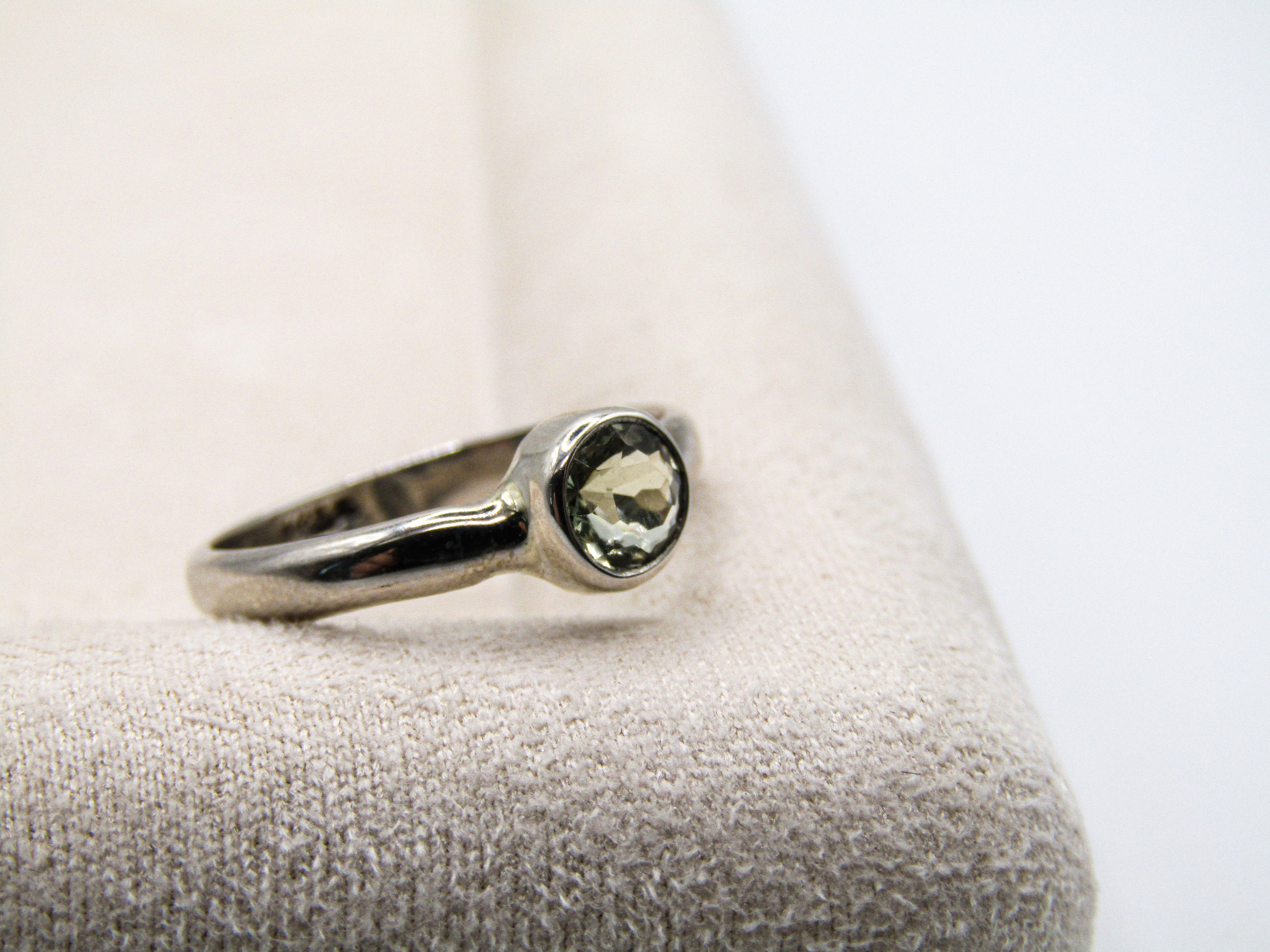 Silver ring with a gemstone on a textured surface
