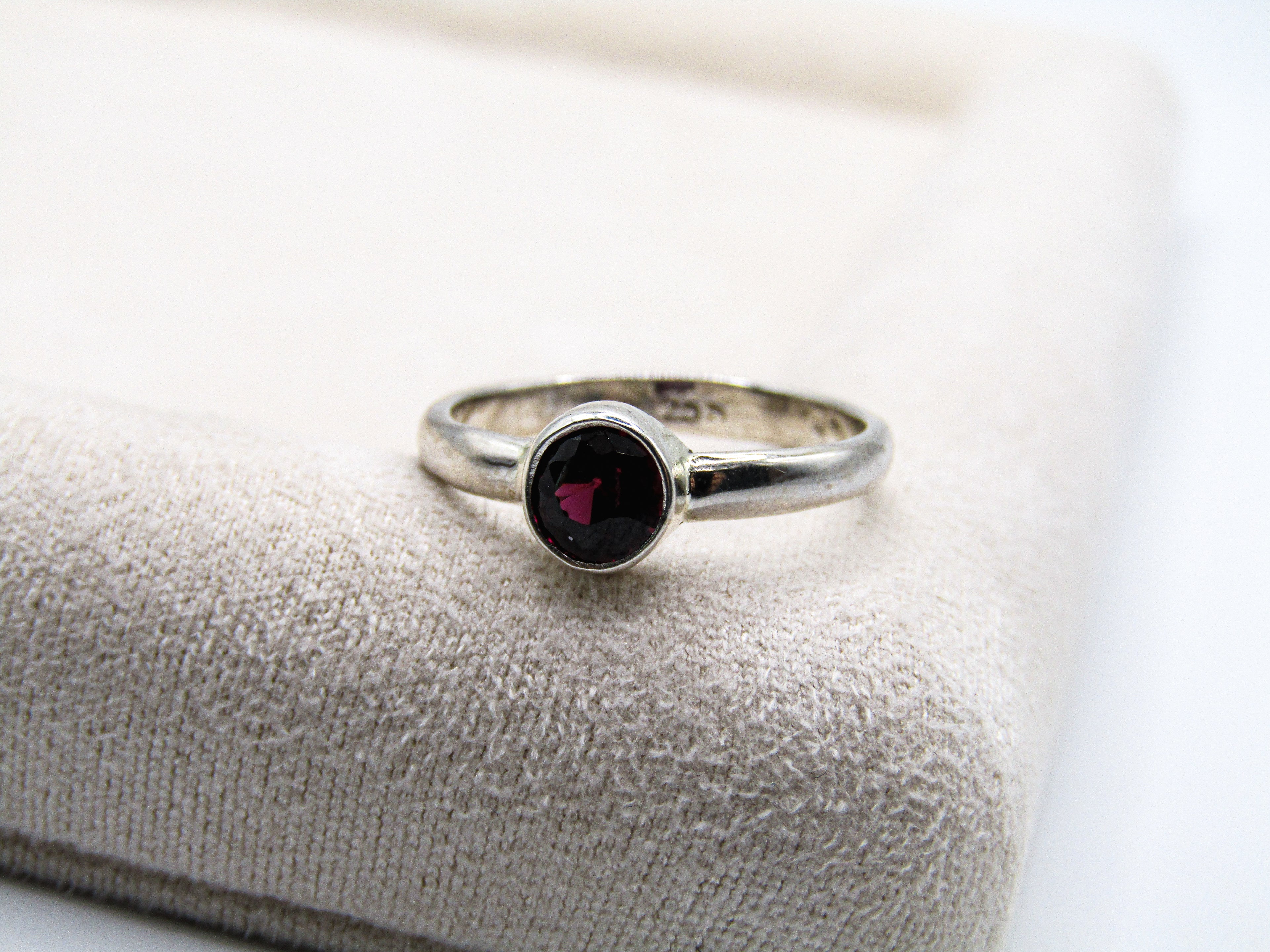 Silver ring with a dark gemstone on a textured surface