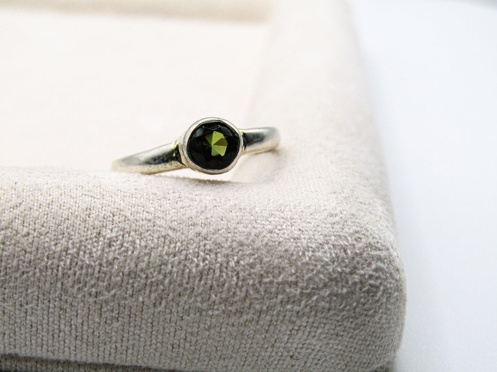Silver ring with a green gemstone on a textured surface