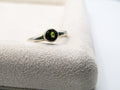 Silver ring with a green gemstone on a textured surface