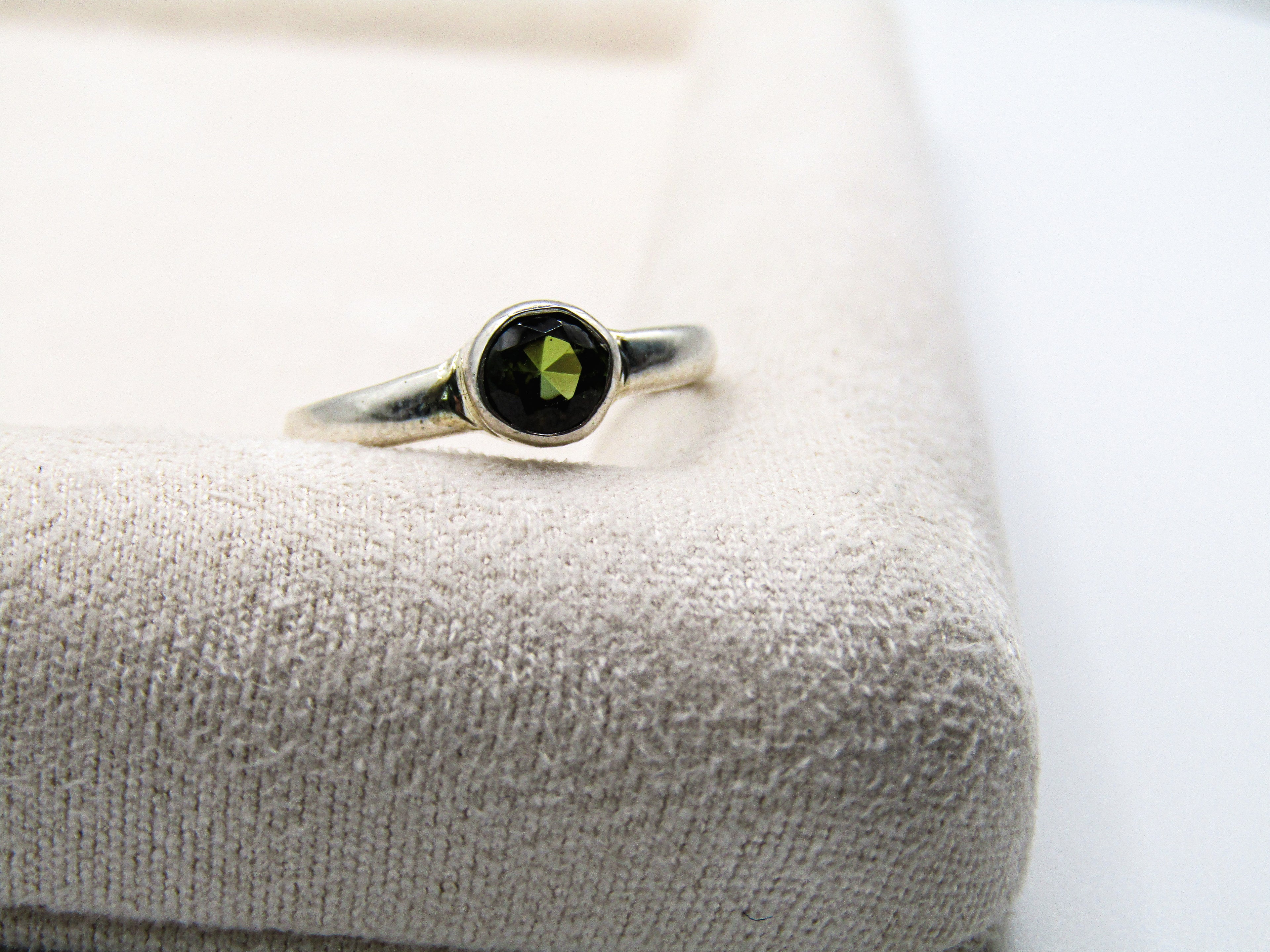 Silver ring with a green gemstone on a textured surface