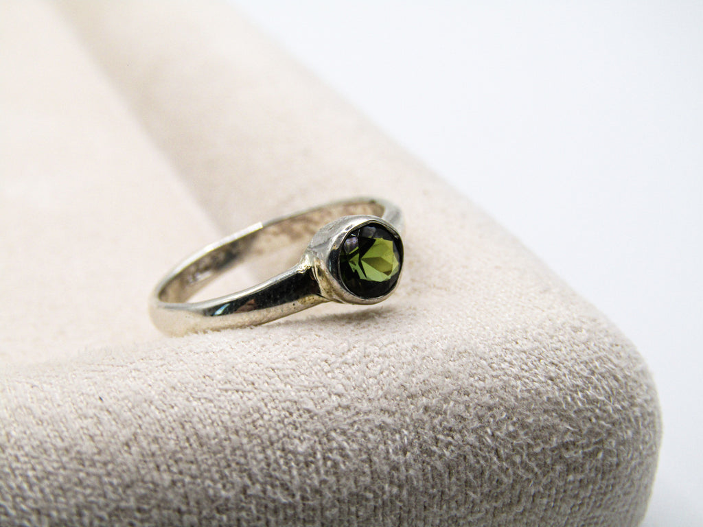 Silver ring with a green gemstone on a textured surface