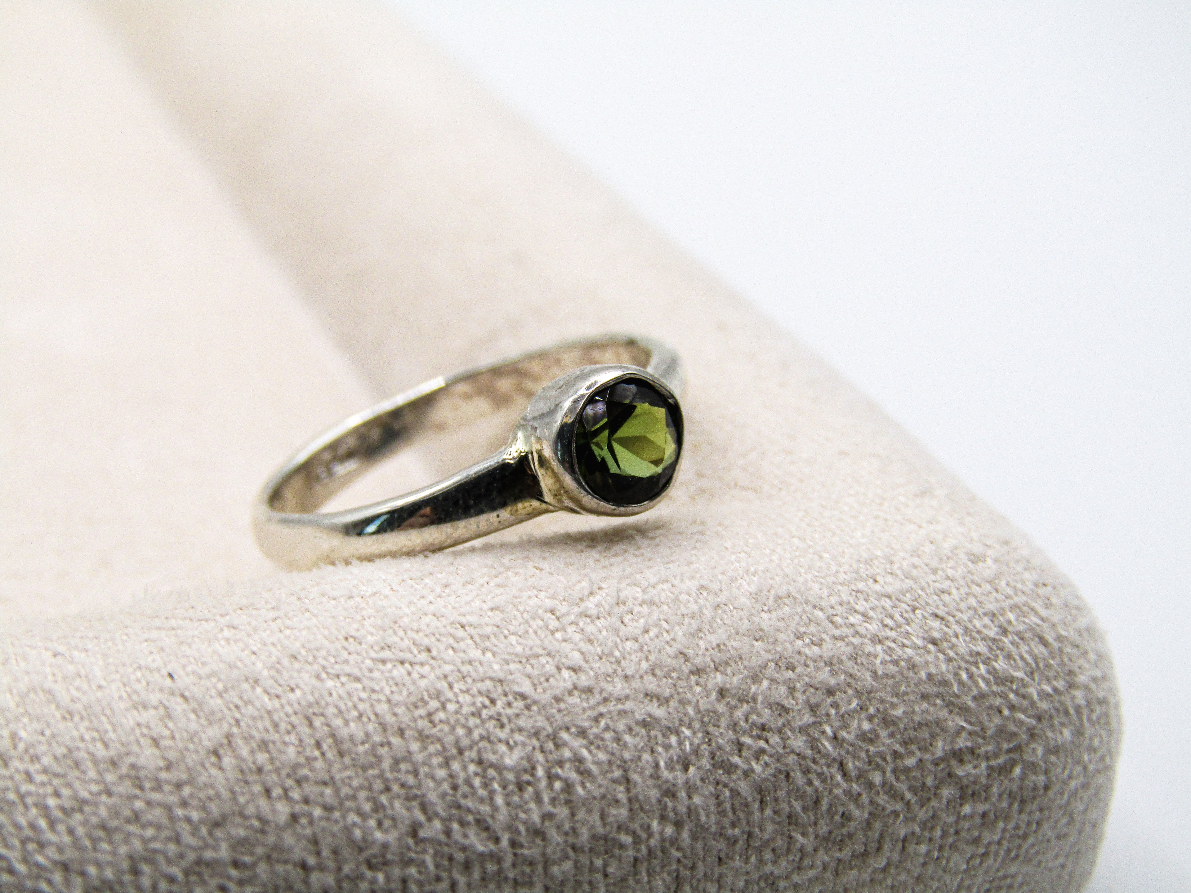 Silver ring with a green gemstone on a textured surface