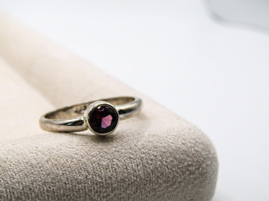 Silver ring with a purple gemstone on a textured surface
