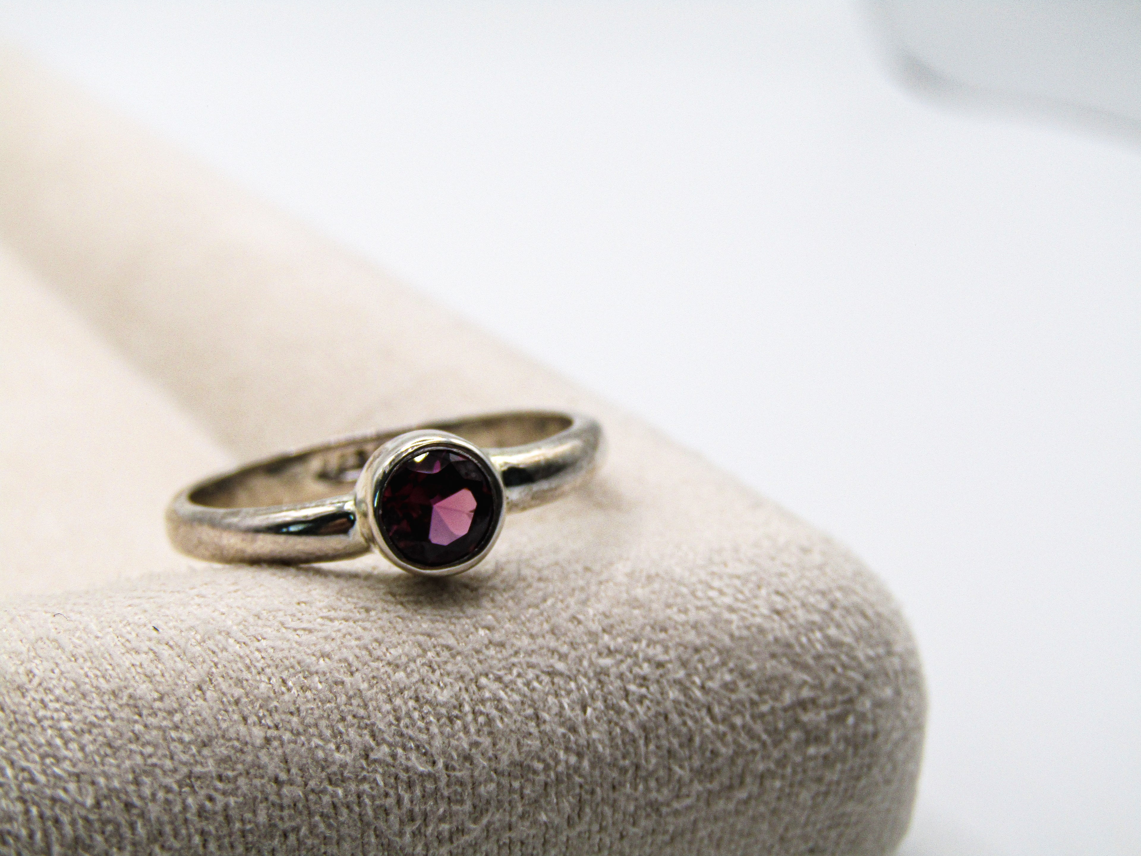 Silver ring with a purple gemstone on a textured surface