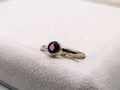 Silver ring with a pink gemstone on a white cushion