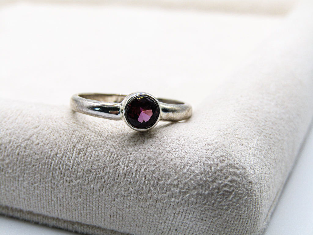 Silver ring with a gemstone on a textured white surface