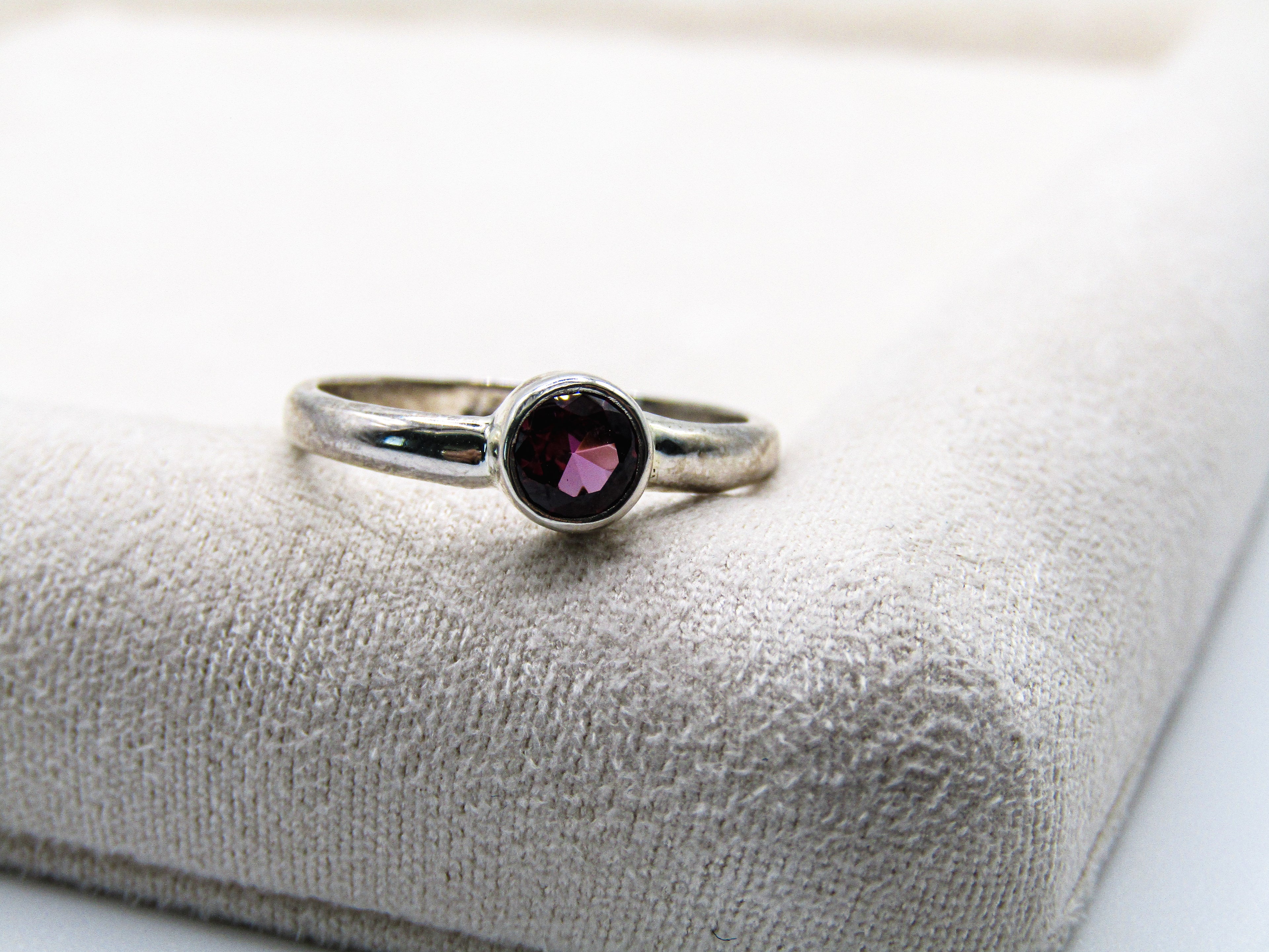 Silver ring with a gemstone on a textured white surface