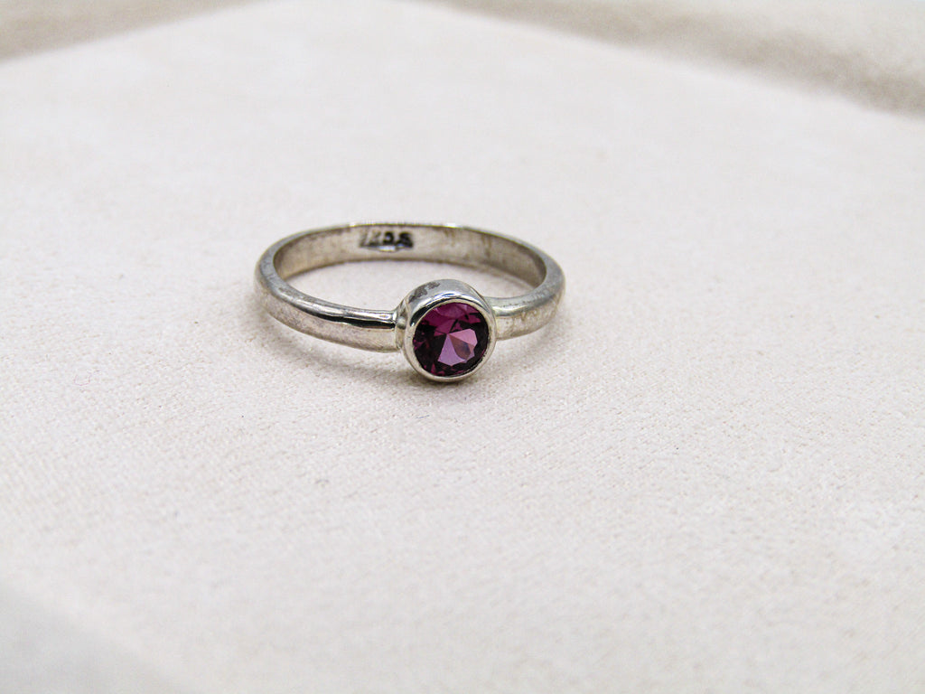 Silver ring with a purple gemstone on a white background