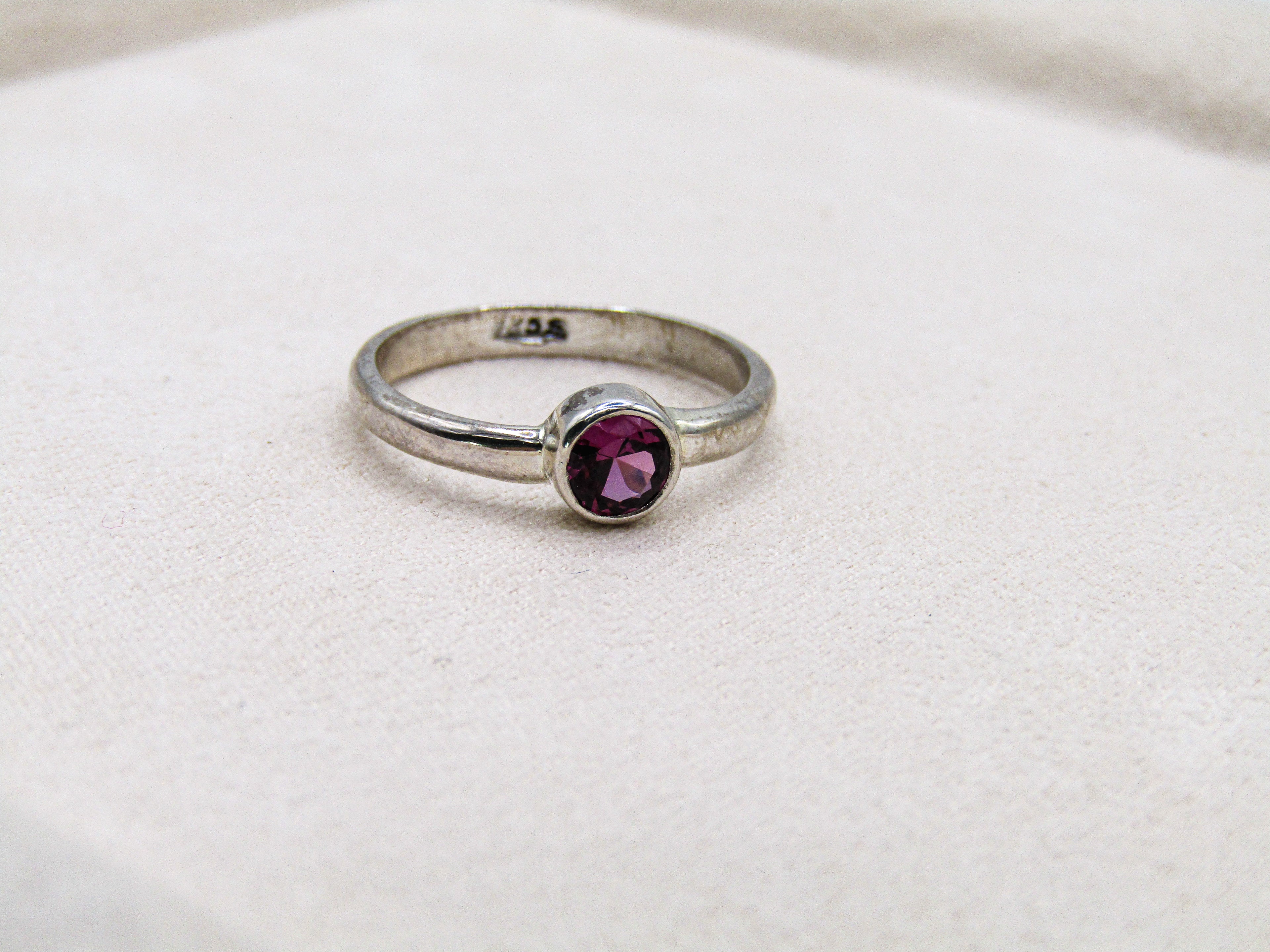 Silver ring with a purple gemstone on a white background