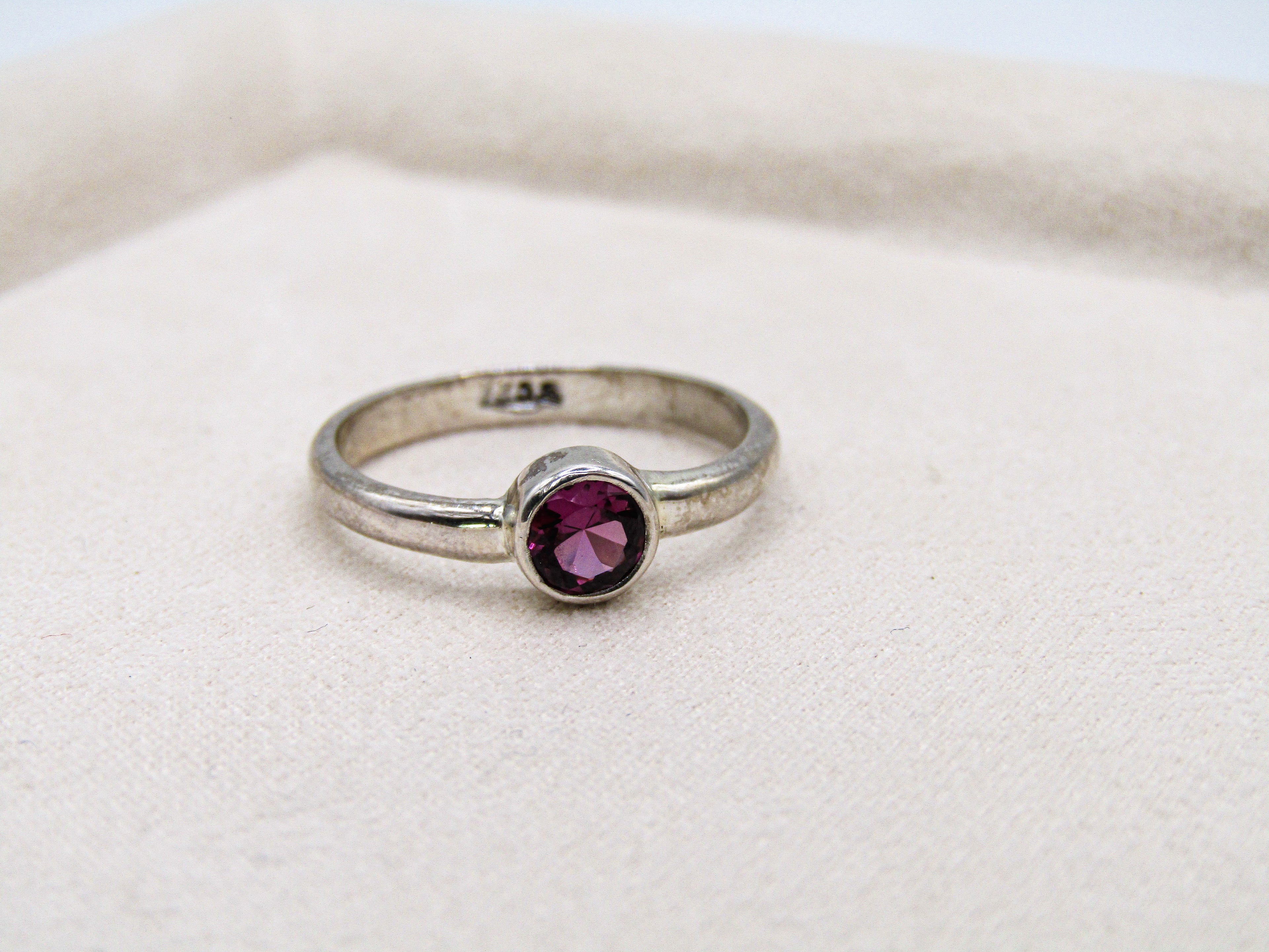 Silver ring with a purple gemstone on a white background