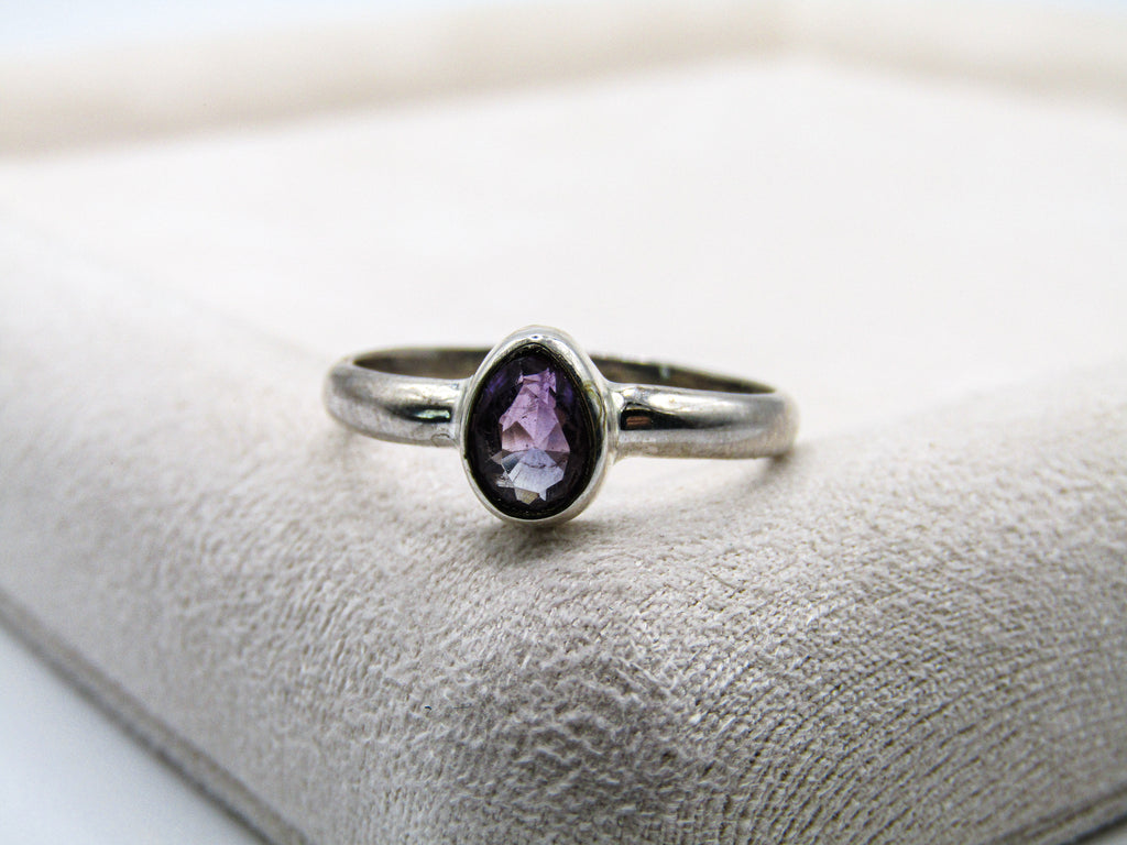 Silver ring with a purple gemstone on a textured surface