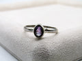 Silver ring with a purple gemstone on a textured surface