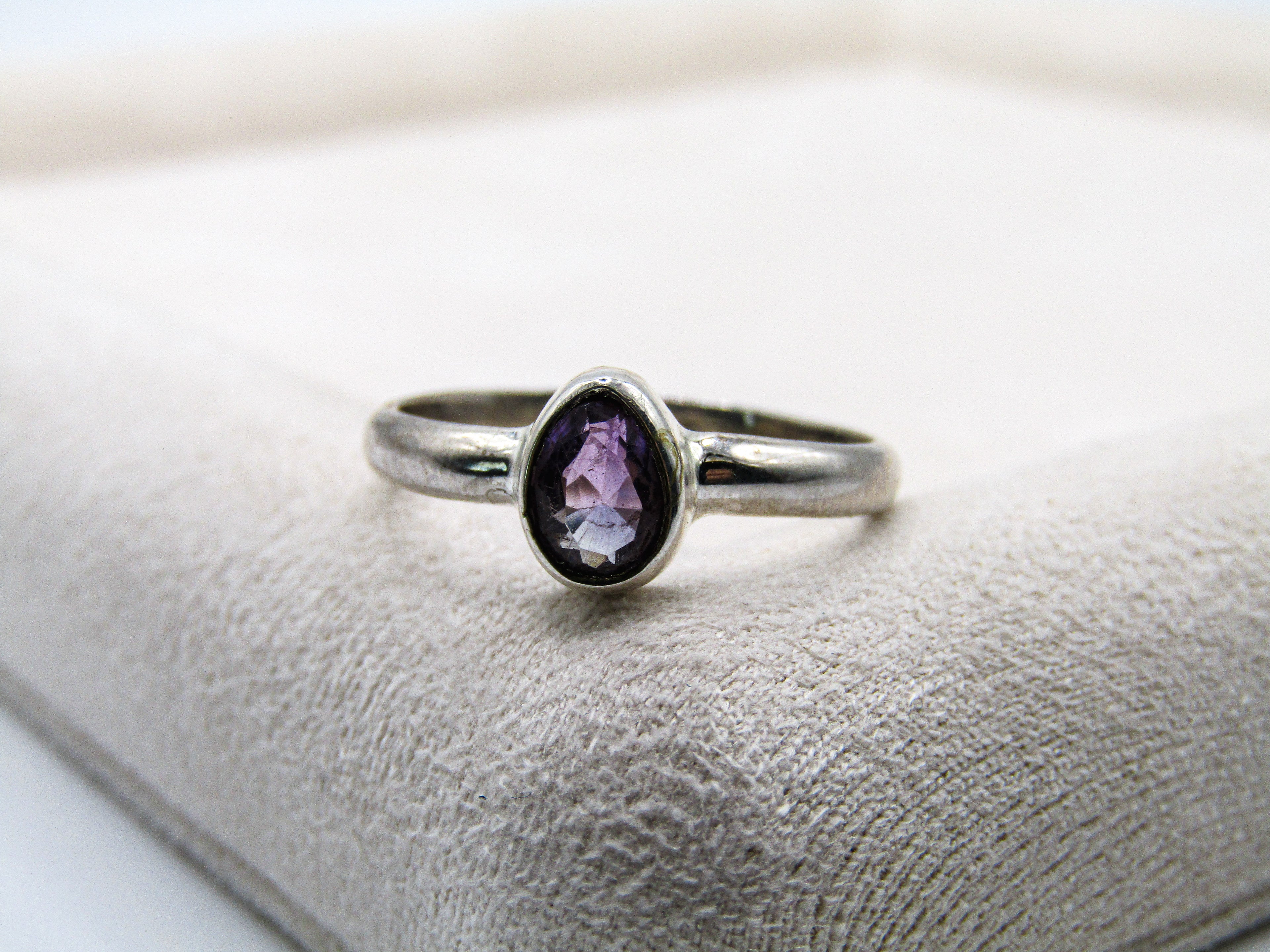 Silver ring with a purple gemstone on a textured surface