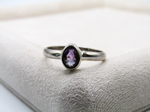 Silver ring with a purple gemstone on a textured surface