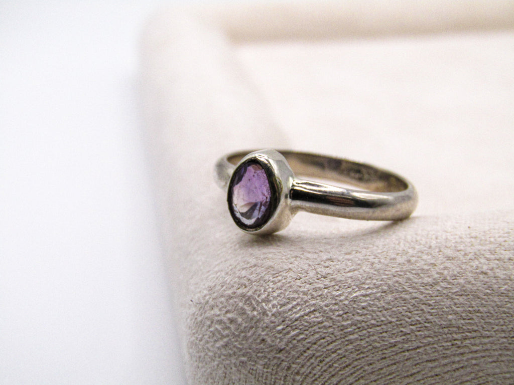 Silver ring with a purple gemstone on a textured surface