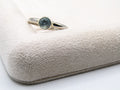 Silver ring with a blue gemstone on a textured beige surface