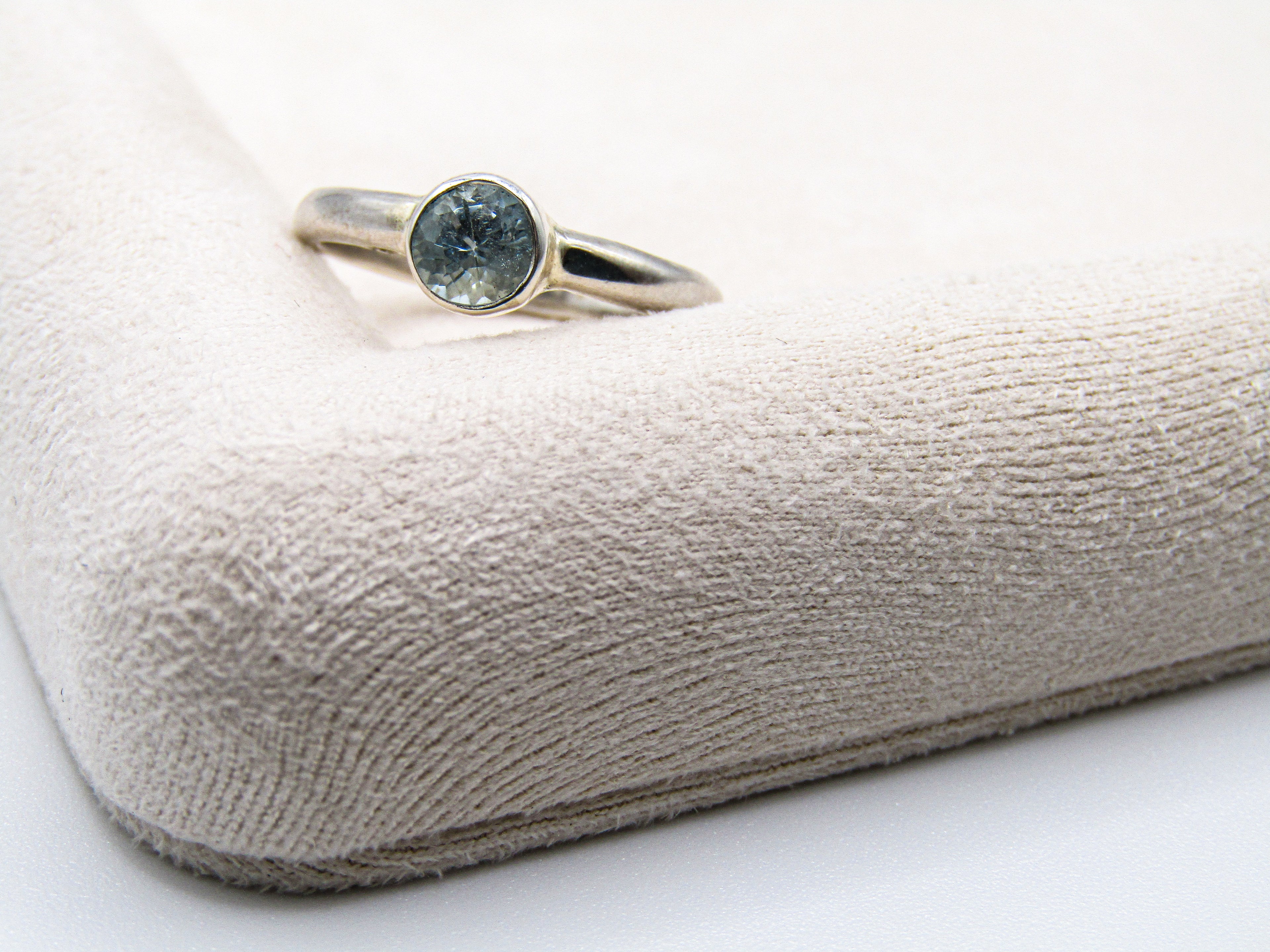 Silver ring with a blue gemstone on a textured beige surface