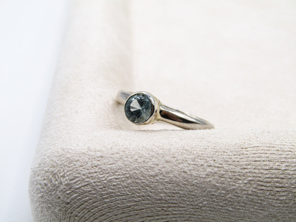 Silver ring with a gemstone on a textured white surface