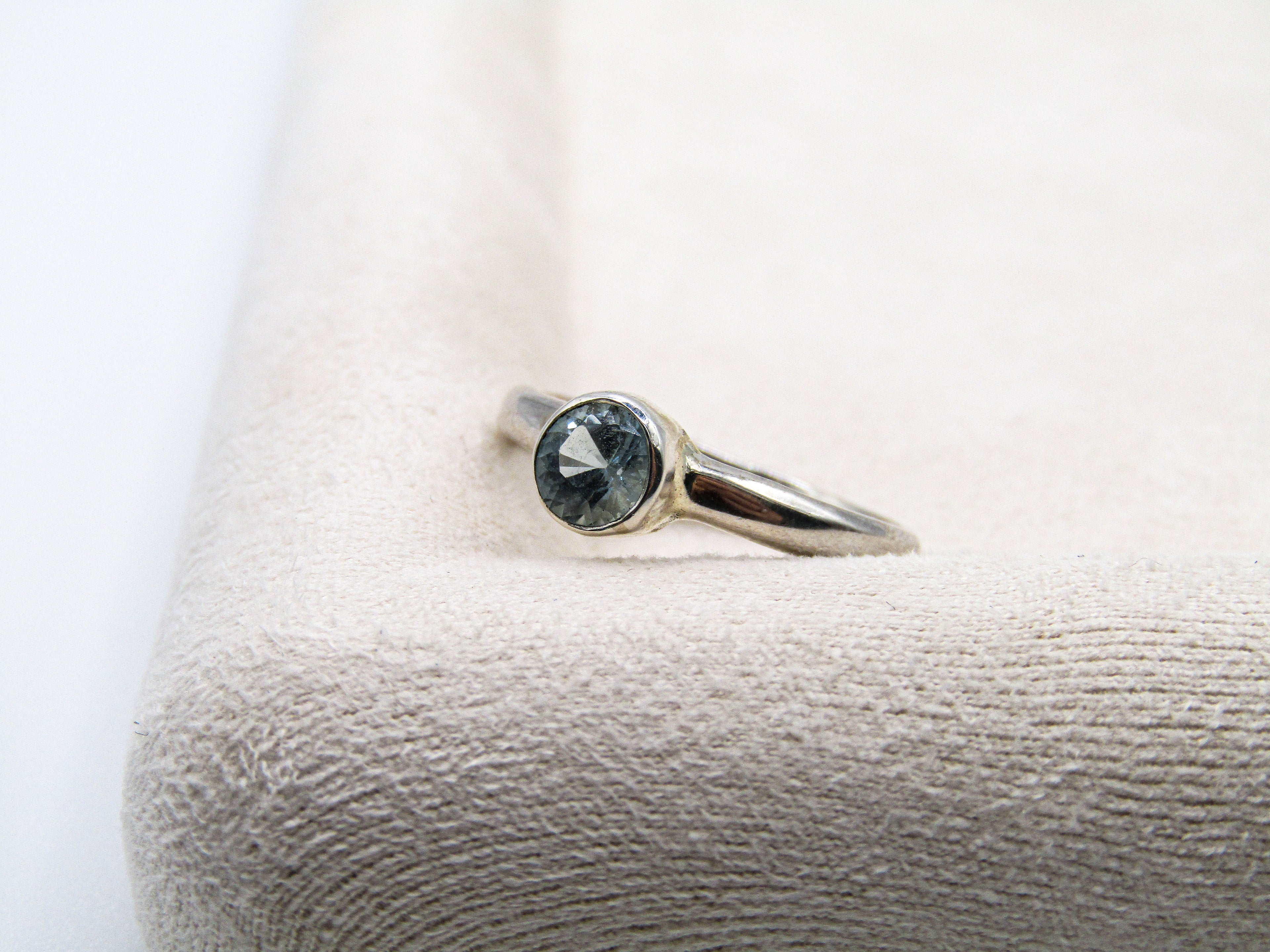 Silver ring with a gemstone on a textured white surface