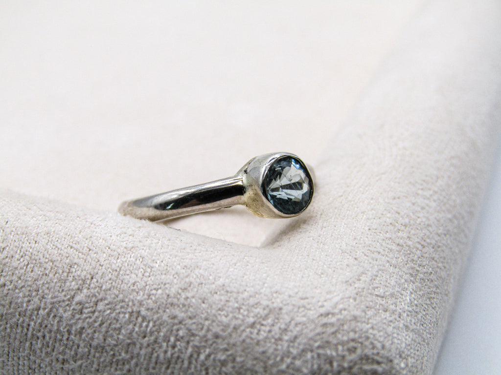 Silver ring with a gemstone on a textured white surface