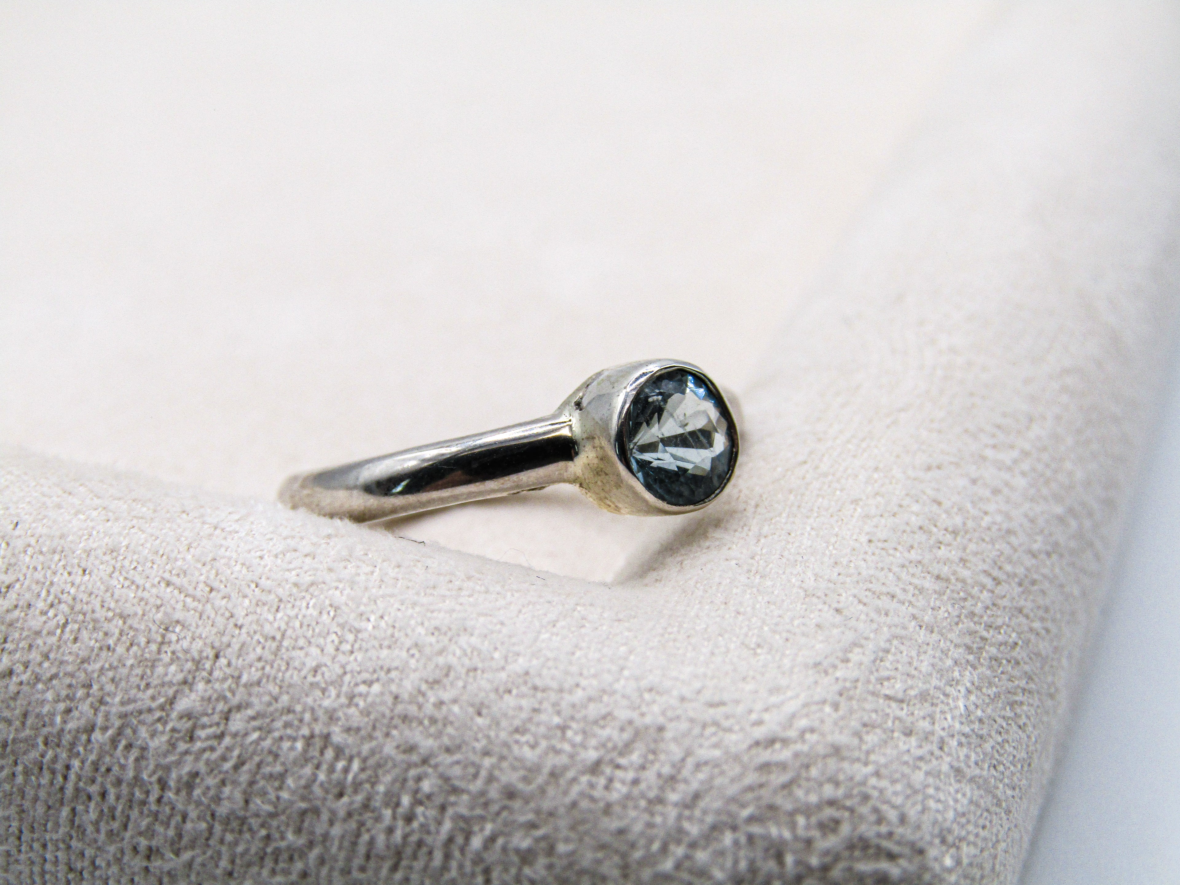 Silver ring with a gemstone on a textured white surface
