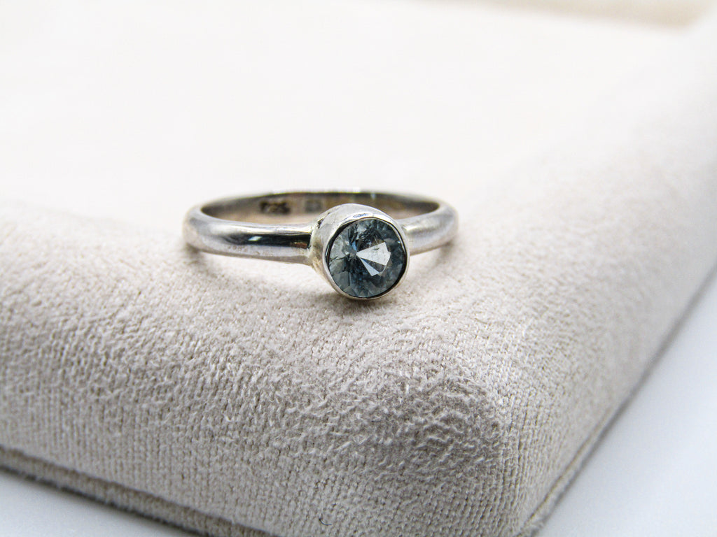 Silver ring with a gemstone on a textured beige surface