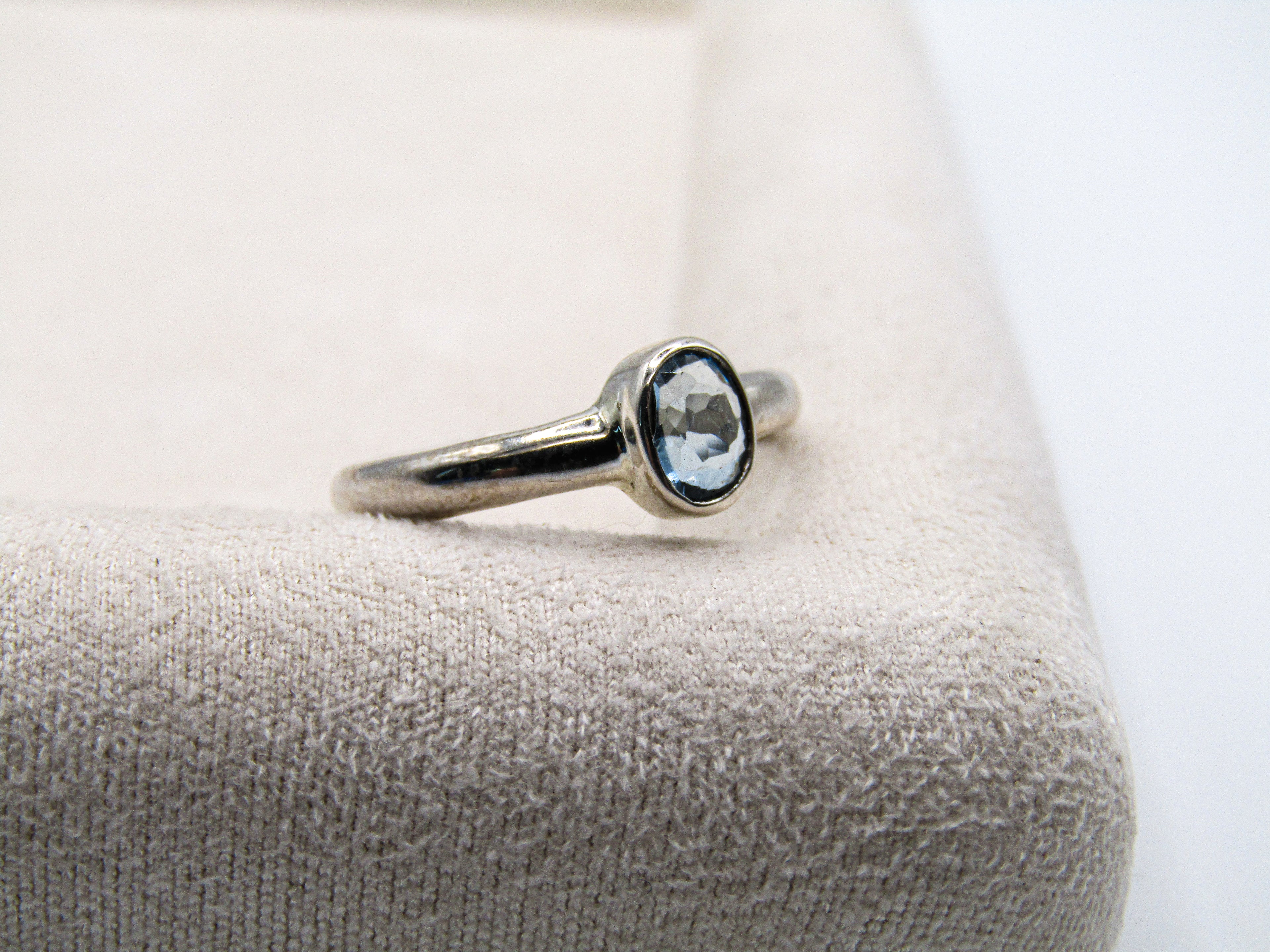 Silver ring with a gemstone on a textured surface