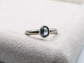Silver ring with a blue gemstone on a white cushion