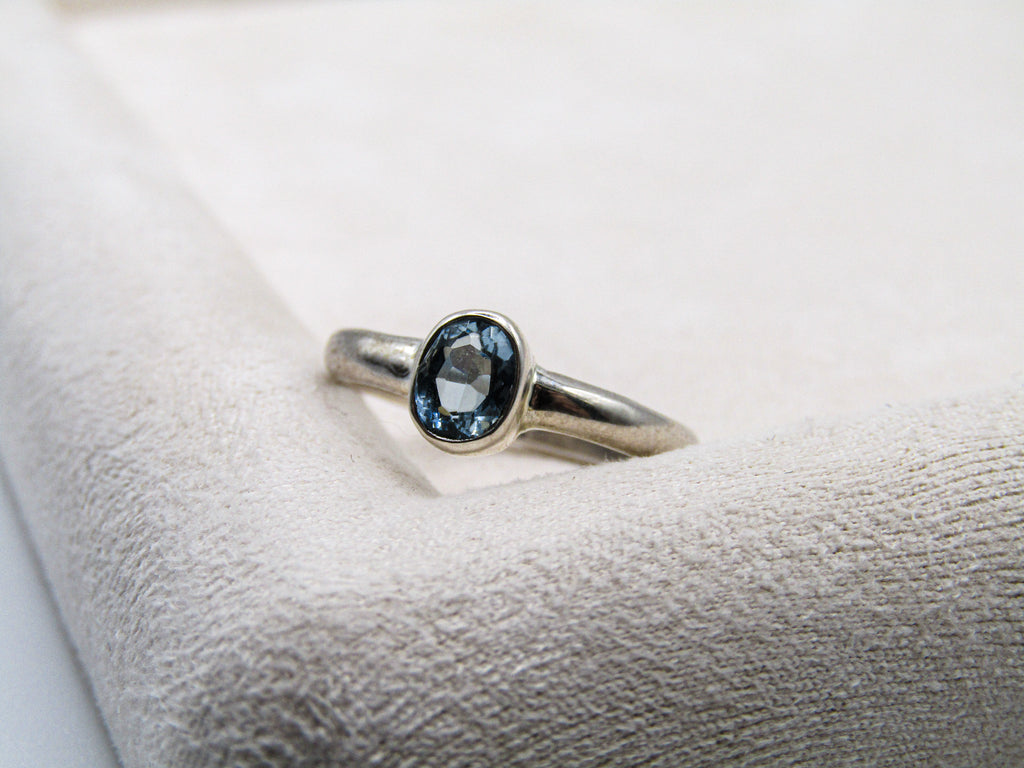 Silver ring with a blue gemstone on a textured white surface