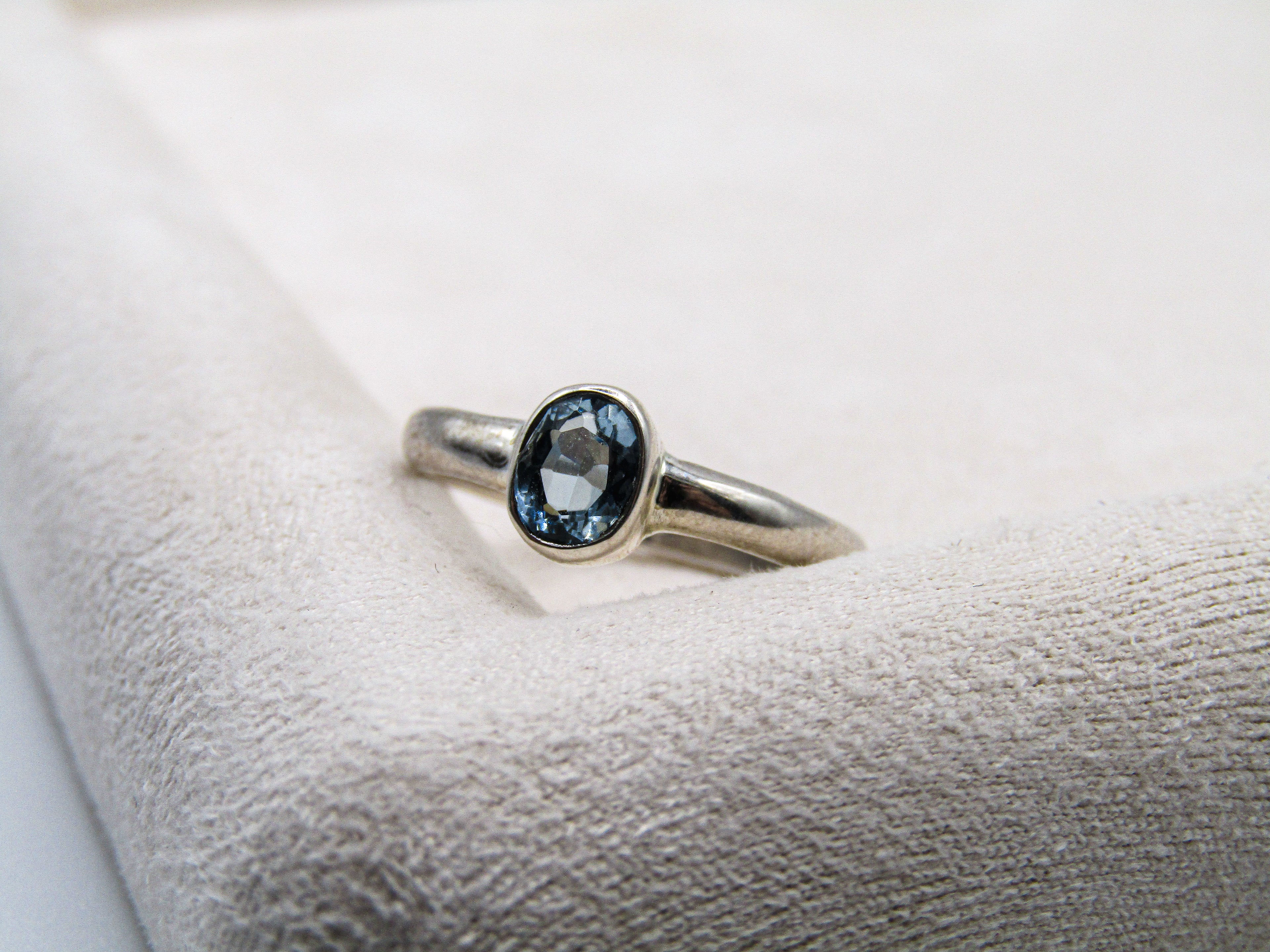 Silver ring with a blue gemstone on a textured white surface
