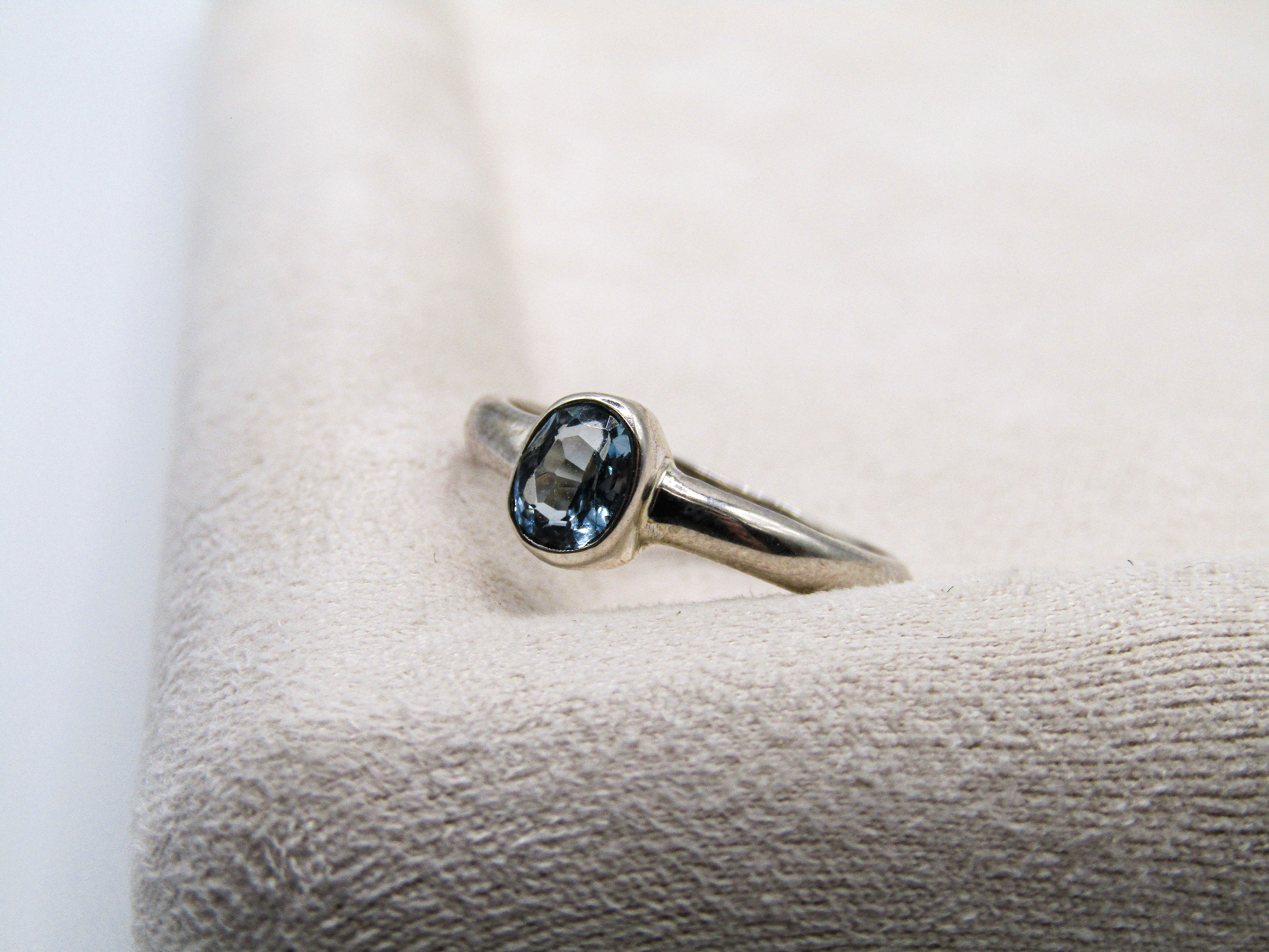 Silver ring with a blue gemstone on a textured white surface