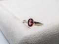 Silver ring with a pink gemstone on a white cushion