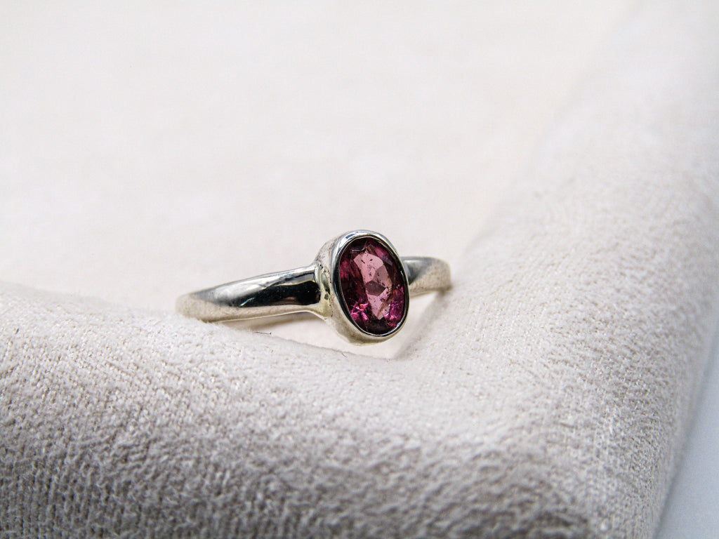 Silver ring with a purple gemstone on a textured surface