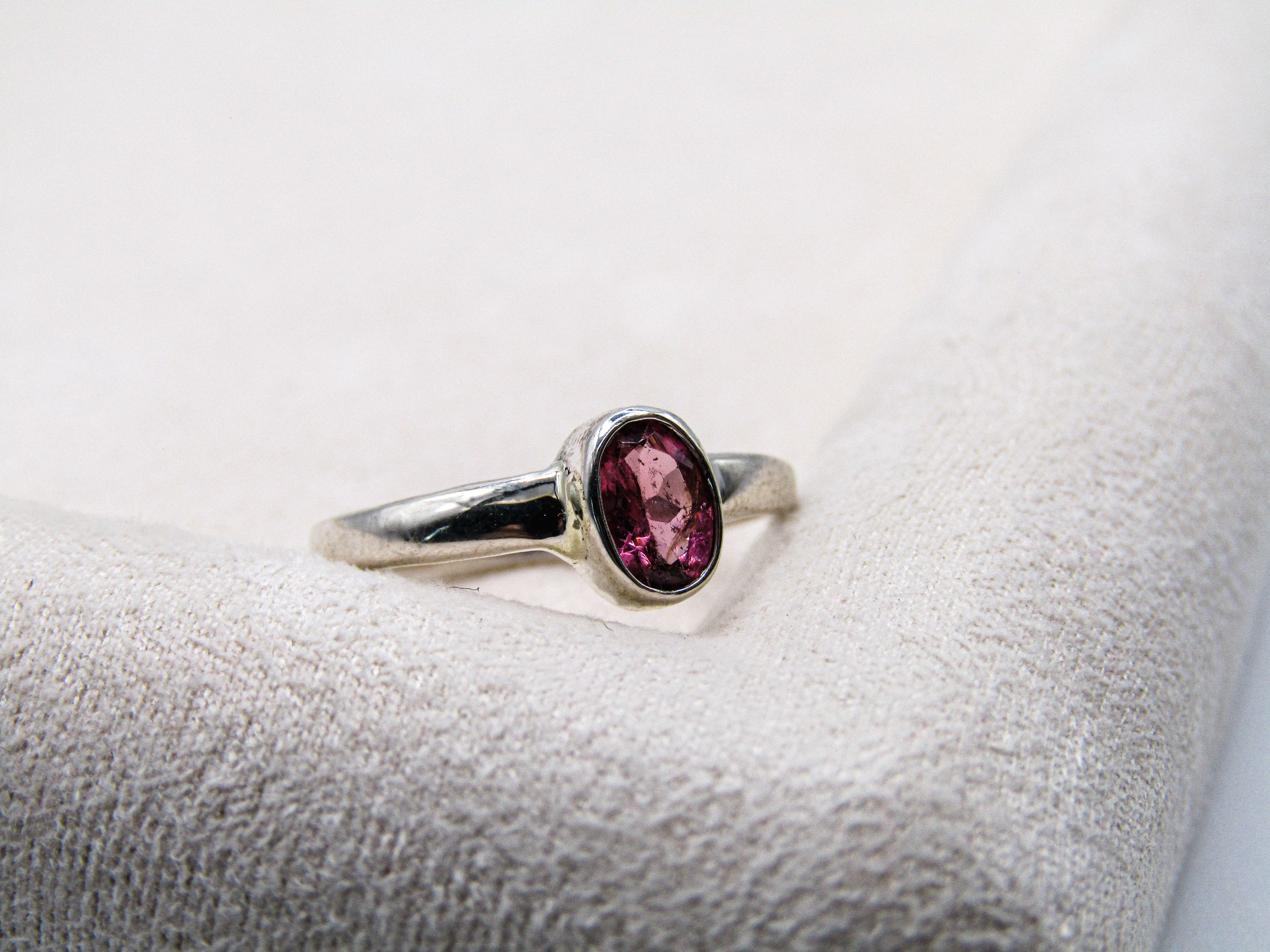 Silver ring with a purple gemstone on a textured surface