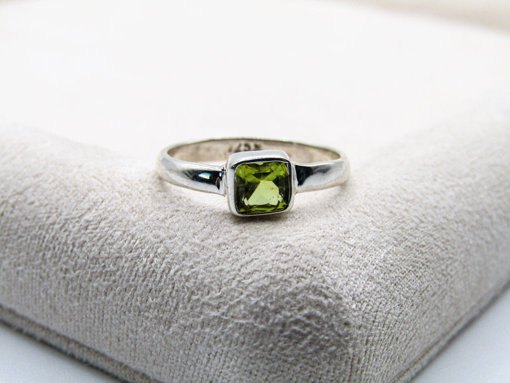 Silver ring with a green gemstone on a textured surface