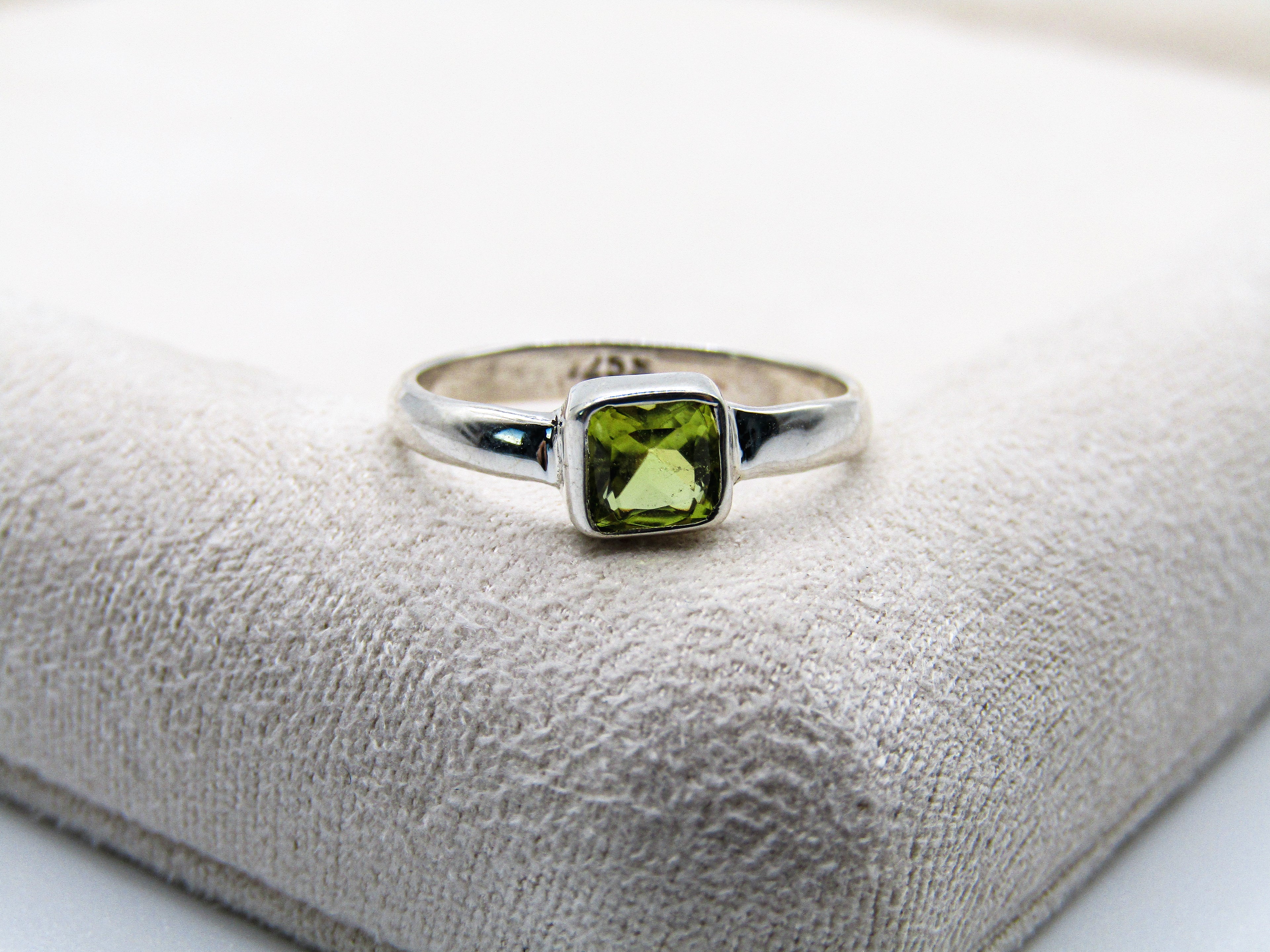 Silver ring with a green gemstone on a textured surface